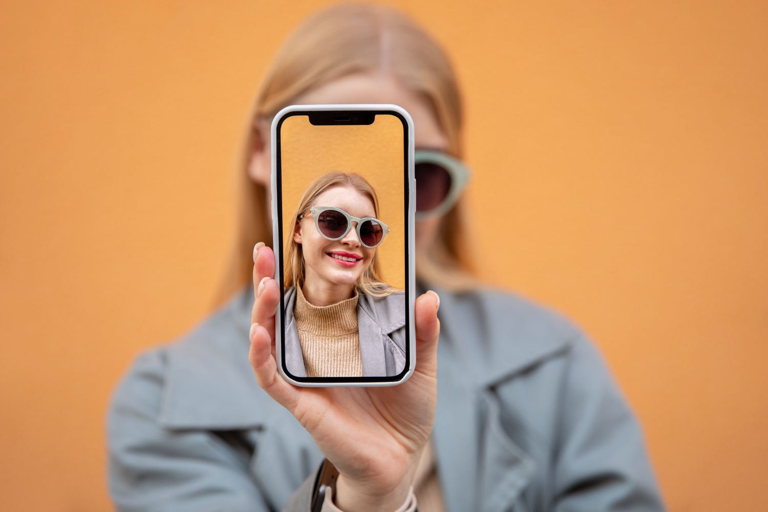 Woman holding a smartphone to take a selfie picture